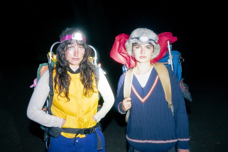 Indie duo The Army, The Navy wearing headlamps and large hiking backpacks outdoors at night for a high-contrast flash press portrait.